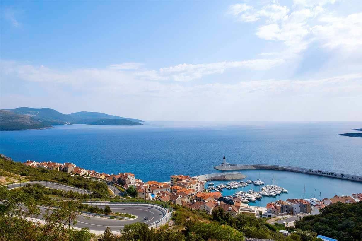 The view of new complex Luštica bay, with villas and marina for yachts in Montenegro. Also, behind it, the open sea is visible with its blue color.